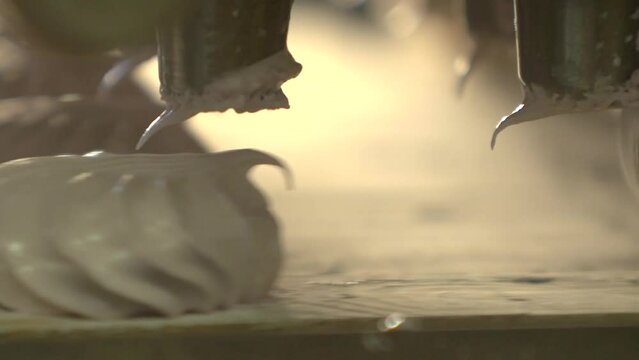 static slow motion macro shot of marshmallow squeezing machine making pink zephyrs in a candy factory