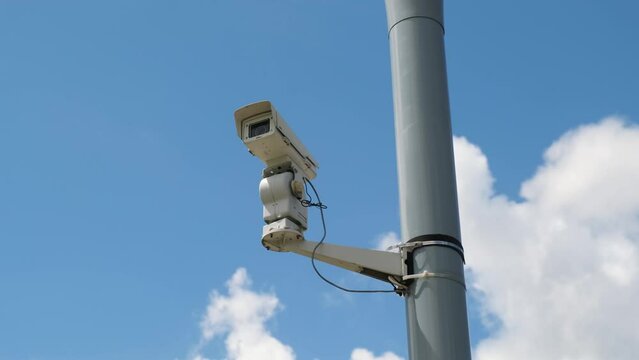 Security video camera moving to scan the area for surveillance purposes. Robotic CCTV recording technology.