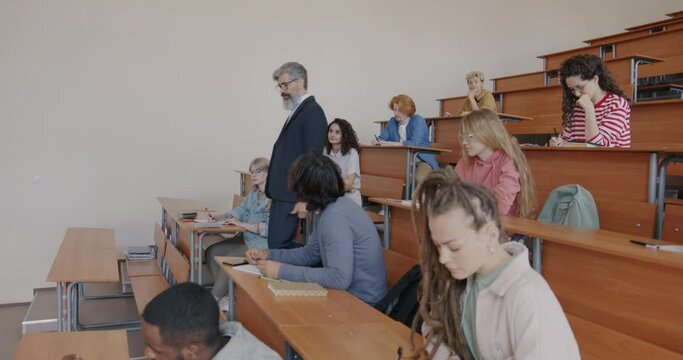 University professor giving lecture to diverse group of students teaching speaking walking in class. Education and intelligent people concept.