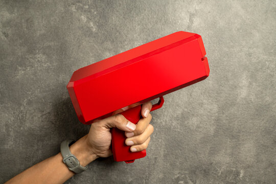 A human hand holding a red money gun