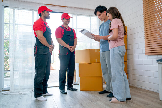 Asian man stand with his wife also check the document of product transportation from delivery men who wait the response from customer during process to send product to customer house.