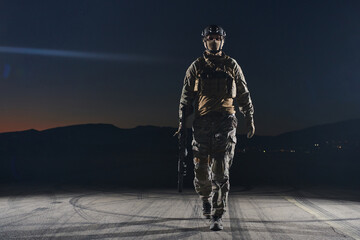 A professional soldier in full military gear striding through the dark night as he embarks on a...