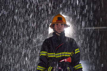 A determined female firefighter in a professional uniform striding through the dangerous, rainy...