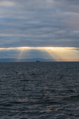 Sunset over the sea with dramatic clouds and rays of light.