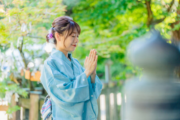 神社で参拝をする浴衣姿の日本人女性
