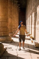 Young man in blue turban walking on the columns of the Edfu Temple near the city of Aswan. Egypt, west bank of the nile in the city of Edfu, Greco-Roman construction, dedicated to Horus - obrazy, fototapety, plakaty