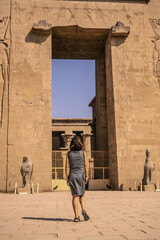 A young tourist at the entrance to the Edfu Temple near the Nile River in Aswan. Egypt, return of...