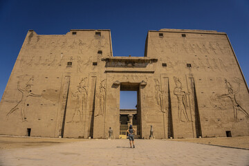 A young tourist at the entrance to the Edfu Temple near the Nile River in Aswan. Egypt, return of...