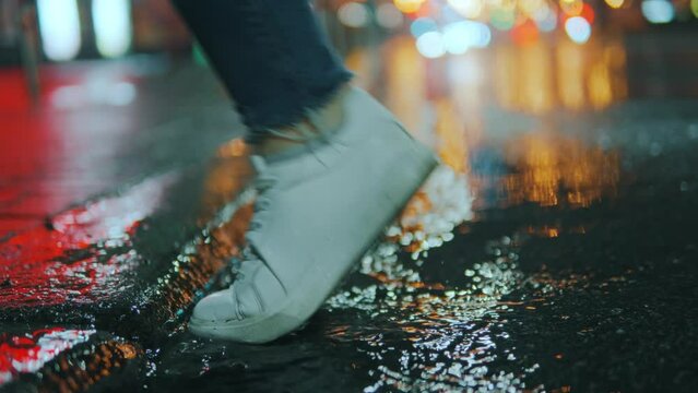 The foot of an unrecognizable person steps into a puddle, breezes fly