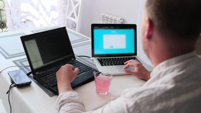 Side view of caucasian man in light shirt passionately typing codes on his laptop. Professional caucasian male software engineer working remotely, demonstrating dedication and expertise in coding and 
