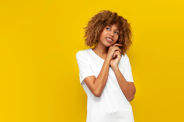 young curly american girl with braces shy and dreaming over yellow isolated background