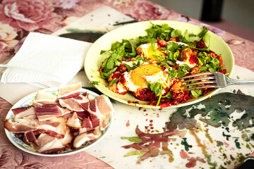 Shakshuka, poached eggs in tomato, olive oil, pepper, onion and garlic sauce and sliced bacon Mediterranean breakfast.