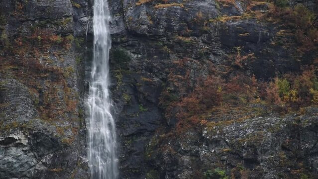 Close up panning up a long waterfall on cliffs in autumn norway wilderness