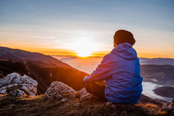 A peaceful man sitting on a mountain top at sunrise with nature landscape healthy lifestyle.