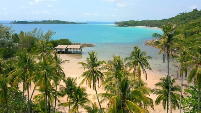 Amazing view of a tropical beach scenery with white sandy beach, turquoise ocean water, and coconut palm trees in Thailand.