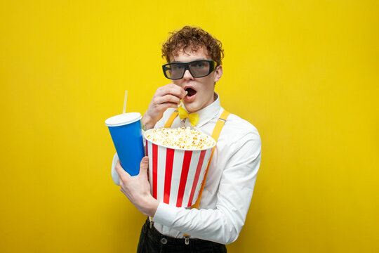 guy in festive outfit in 3d glasses watches movie with popcorn, nerd student in bow tie and suspenders cinema viewer