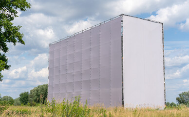 Blank billboard for outdoor advertising standing in green meadow. Billboard surface with empty...