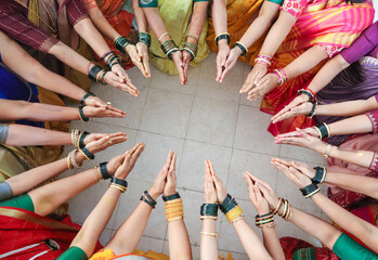  An Elegant picture of a Hindu Wedding ritual where a group of ladies showcase their vibrant colored bangles on their hands in a certain posture and pattern in India.
