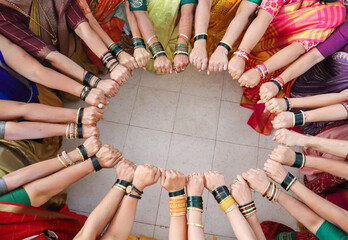  An Elegant picture of a Hindu Wedding ritual where a group of ladies showcase their vibrant colored bangles on their hands in a certain posture and pattern in India.