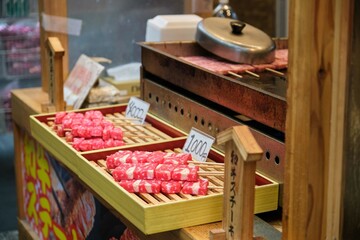 Raw wagyu kobe beef skewers ready for grilling at a stand in a market in Osaka, Japan.