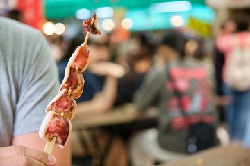 Hand holding squid skewer at Osaka market, Japan.