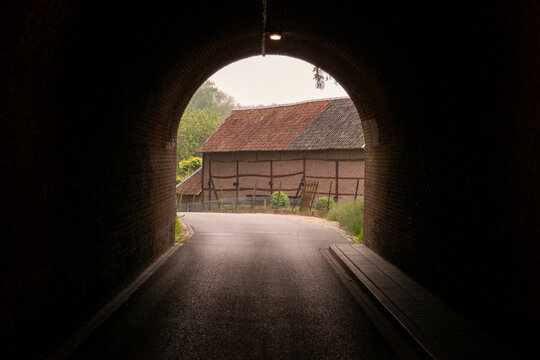 View through railway tunnel at old barn half timbered wood house in Limburg, The Netherlands