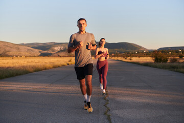 A handsome young couple running together during the early morning hours, with the mesmerizing sunrise casting a warm glow, symbolizing their shared love and vitality