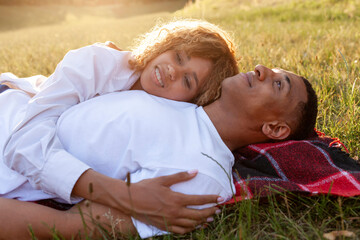 african american romantic young couple lies on the grass in the park and sleeps in nature, happy family rests - Powered by Adobe