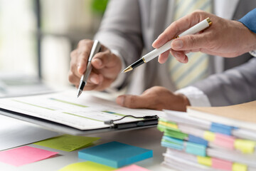 Group of business people meeting to plan, think, analyze, point to graph and business growth to plan new business expansion in the future using a laptop and a calculator.