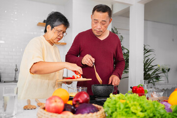 Asian elderly couple cooking in kitchen to prepare dinner