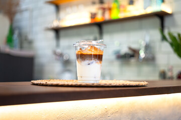 An ice milk coffee in plastic cup and served on counter bar. Drink and beverage object photo.