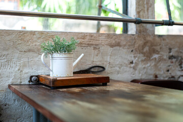 A metal flowerpot with artificial leaf that placed on wooden table at the classic style building. Interior decoration object photo, selective focus.