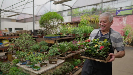 One Happy older male employee carrying Flowers inside Plant Store. Local business shop of senior person working with gardening