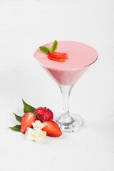 Strawberry cream jelly, Panna Cotta, decorated with fresh strawberry slices, in a martini glass. White background. Copy space