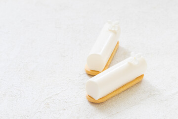 Two Vegan desserts. Vanilla cream dessert bar decorated with a small white flower. On cookies. White background. Copy space