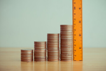 Orange measuring ruler measure growth stack coins on wooden table white wall background copy space....