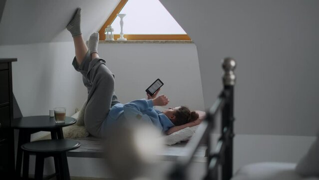 Millenial woman reads e-book in her cozy apartment, 4k