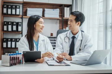 Obraz premium Asian medical doctors specialist in white lab coats working together, discussing at meeting about blood test results, anemia, infection in the bloodstream, diabetes
