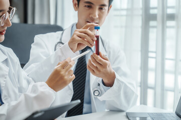 Asian medical doctors specialist in white lab coats working together, discussing at meeting about blood test results, anemia, infection in the bloodstream, diabetes