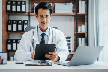 Asian medical doctors specialist in white lab coats , research or online consultation, discussing at meeting on video conference on laptop at desk in medical industry.