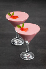 Vegan dessert. Strawberry cream Panna Cotta, decorated with fresh strawberry slices, in a martini glass. Dark grey background	