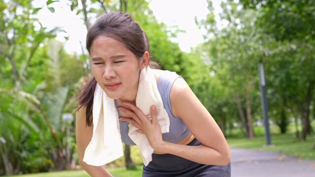 Sport asian woman gets tired and get dizzy, feel bad pain and suffer from heat stroke outdoors when jogging or exercise outdoor with strong sunlight in summer season. Heatstroke and heat wave concept.