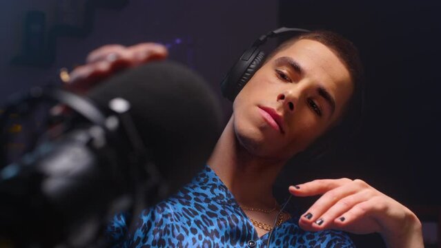 A gay guy is recording a podcast about the LGBT community. A recording studio to create a live stream, sexually touches the microphone like a penis. A man creates a blog on radio about queer people