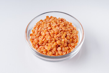 Fototapeta na wymiar dried orange lentil flakes in a glass plate on a white background