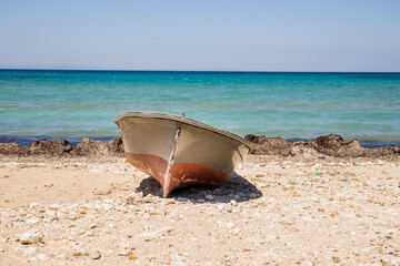A wooden boat on the quiet beach with no one, by the sea