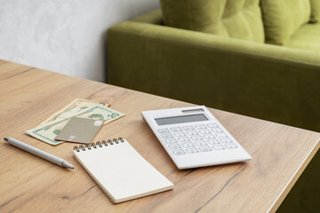 Calculator, money, journal and pan on the desk agaisnt green sofa. oncept of estimate utility costs