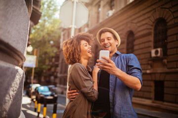 Young couple taking a selfie while walking on a city street