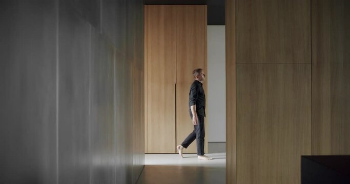 Man goes into the house. Cozy Modern Furniture Design. Luxury Elegant Room. Modern contemporary Minimalist living room with wooden wall. Luxury Modern House Interior. Minimalist Home Interior.