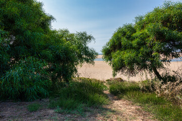 Serene Lagoa de Albufeira beach in Sesimbra, Portugal, featuring a wide sandy shore and calm lagoon waters under a clear blue sky.