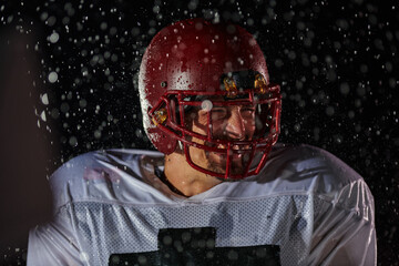 American Football Field: Lonely Athlete Warrior Standing on a Field Holds his Helmet and Ready to Play. Player Preparing to Run, Attack and Score Touchdown. Rainy Night with Dramatic Fog, Blue Light